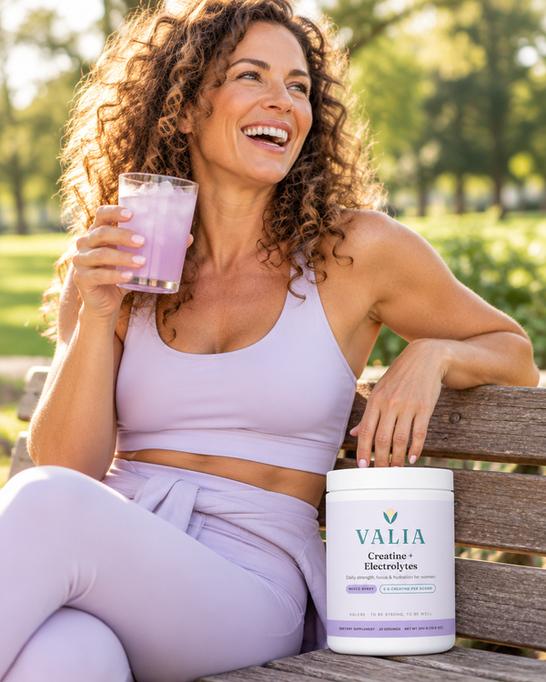 Woman laughing with an iced VALIA drink after a walk
