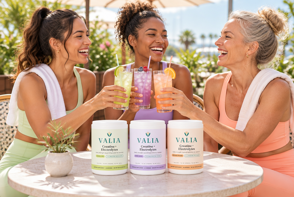 Three friends clinking iced VALIA drinks at a sunny café